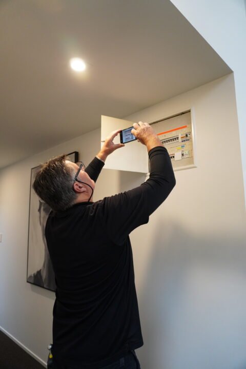 Inspector checking a home’s switchboard for electrical safety.