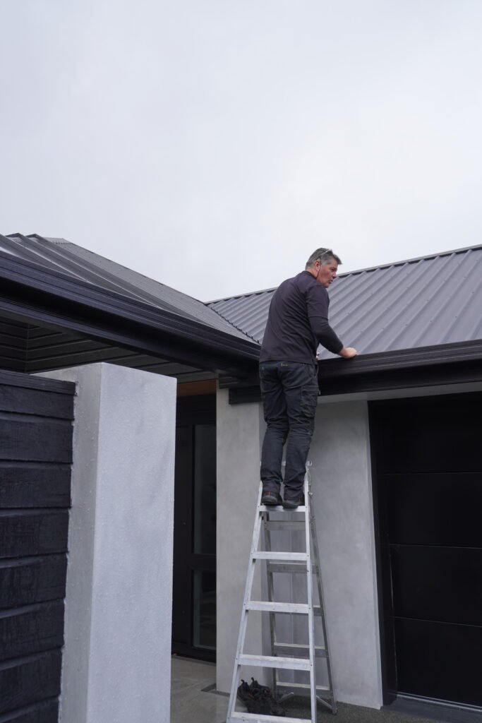 Inspector checking gutters for blockages, leaks, and water drainage issues.